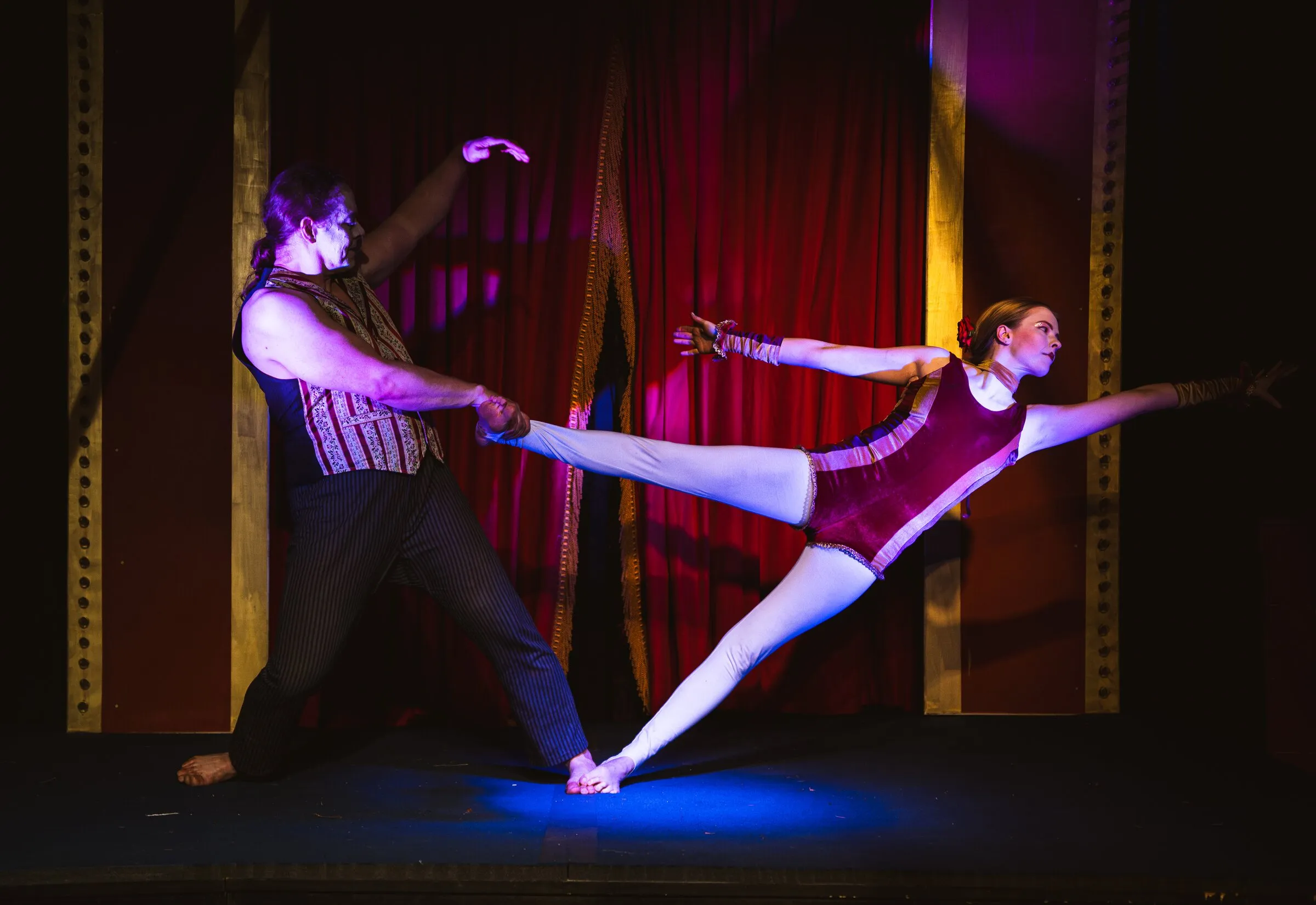 A Kuroneko Circus acrobatic duo, one partner holding the other out in a long low lunge across the stage