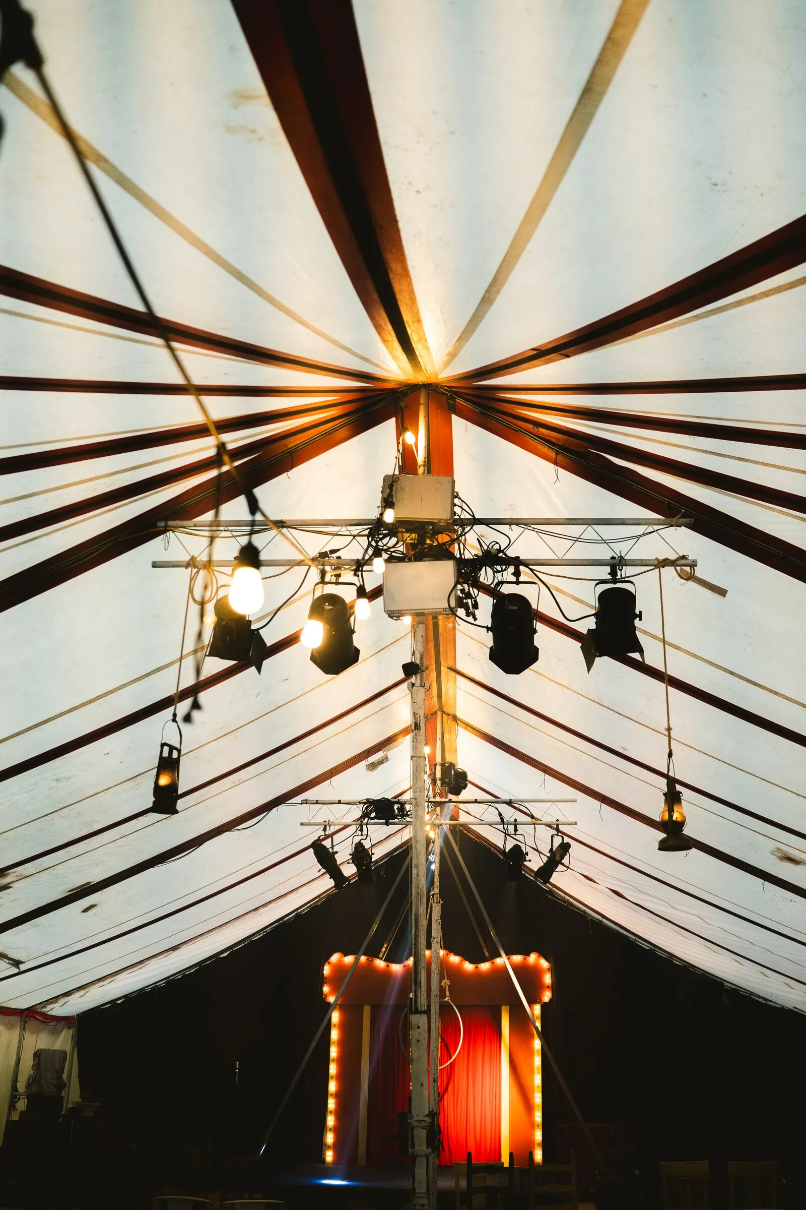 Looking up the center pole of the Kuroneko Circus big top at the striped canvas and lighting rig