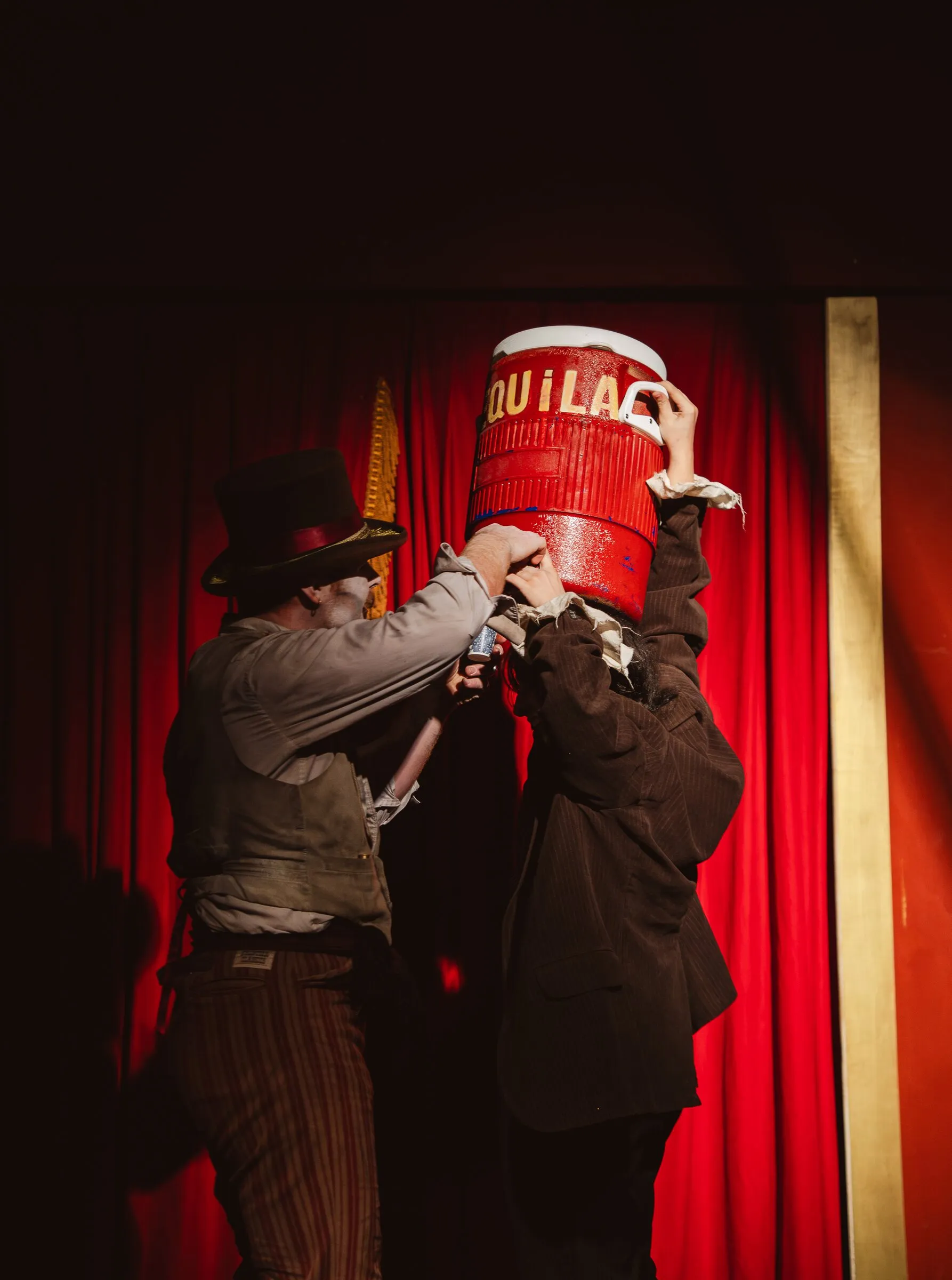 Two Kuroneko Circus clowns struggling over an upturned water cooler in a slapstick routine
