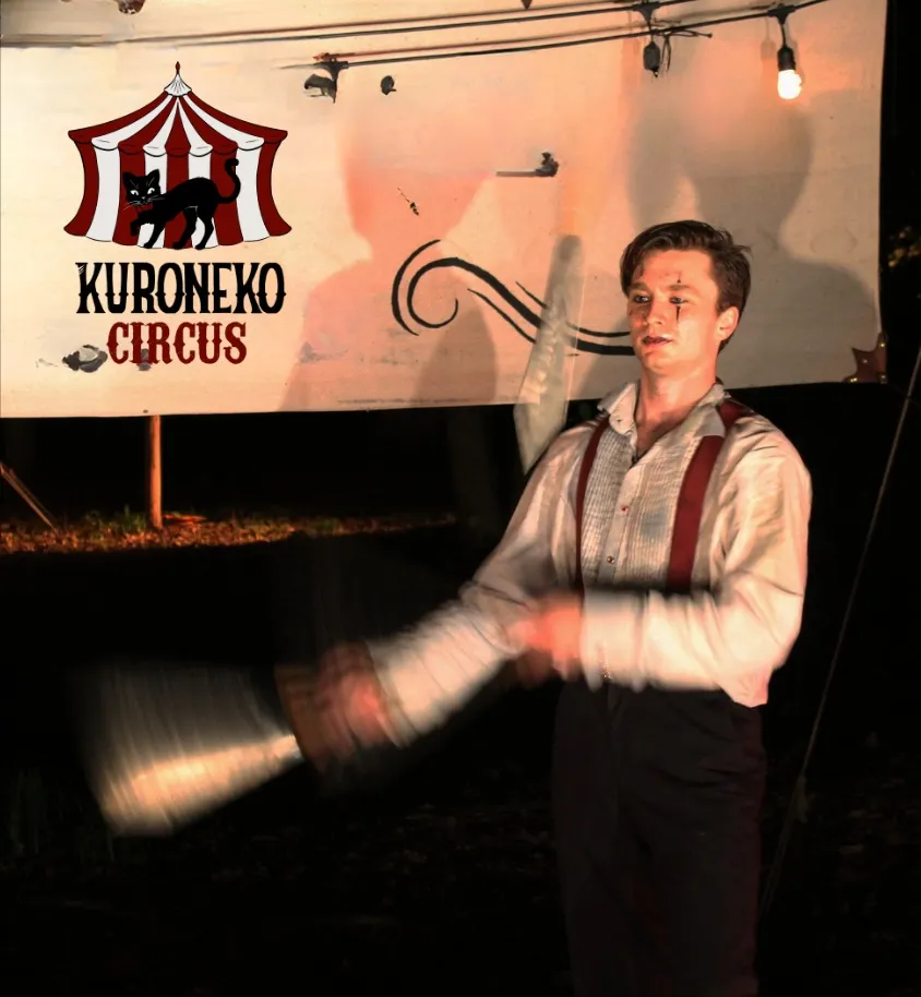 A Kuroneko Circus juggler mid-routine in a blur of motion during a nighttime North Carolina performance